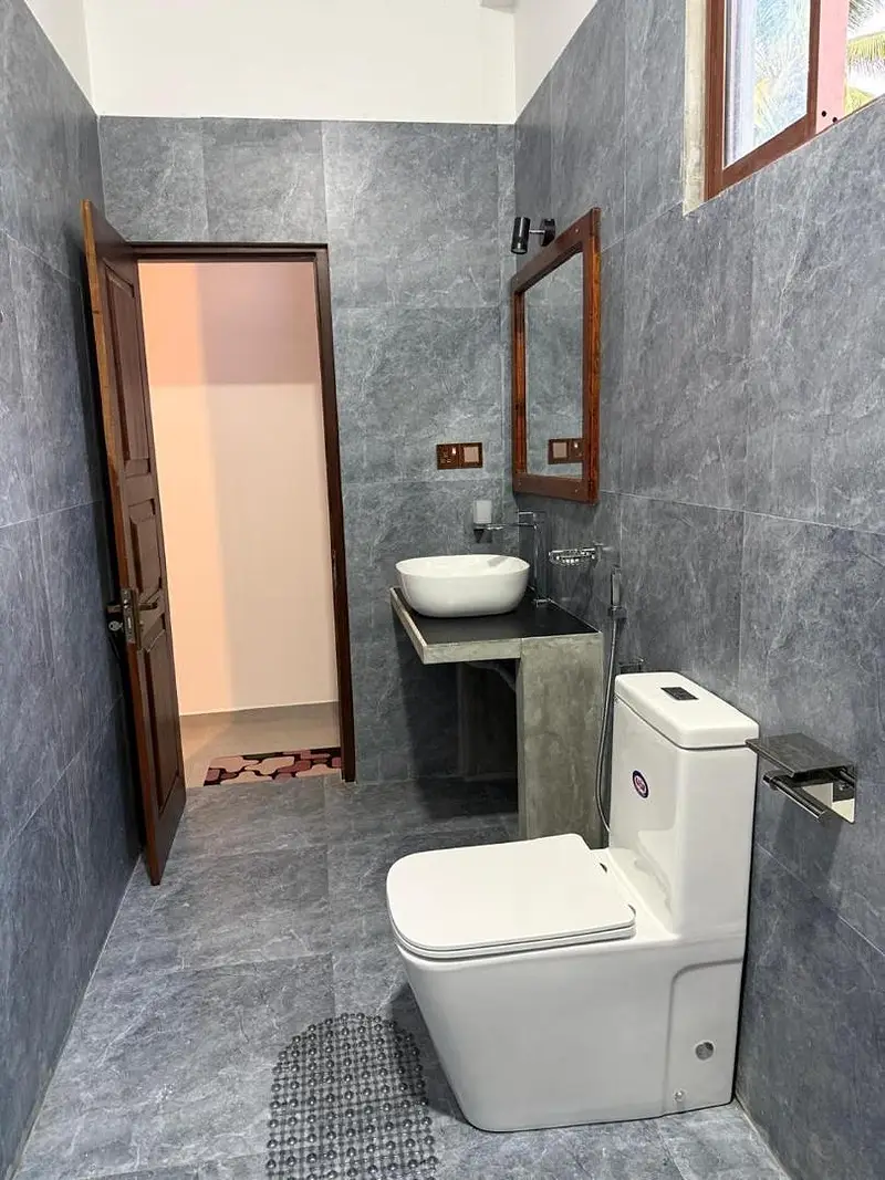 Grey tiled bathroom with a modern WC and timber-framed window