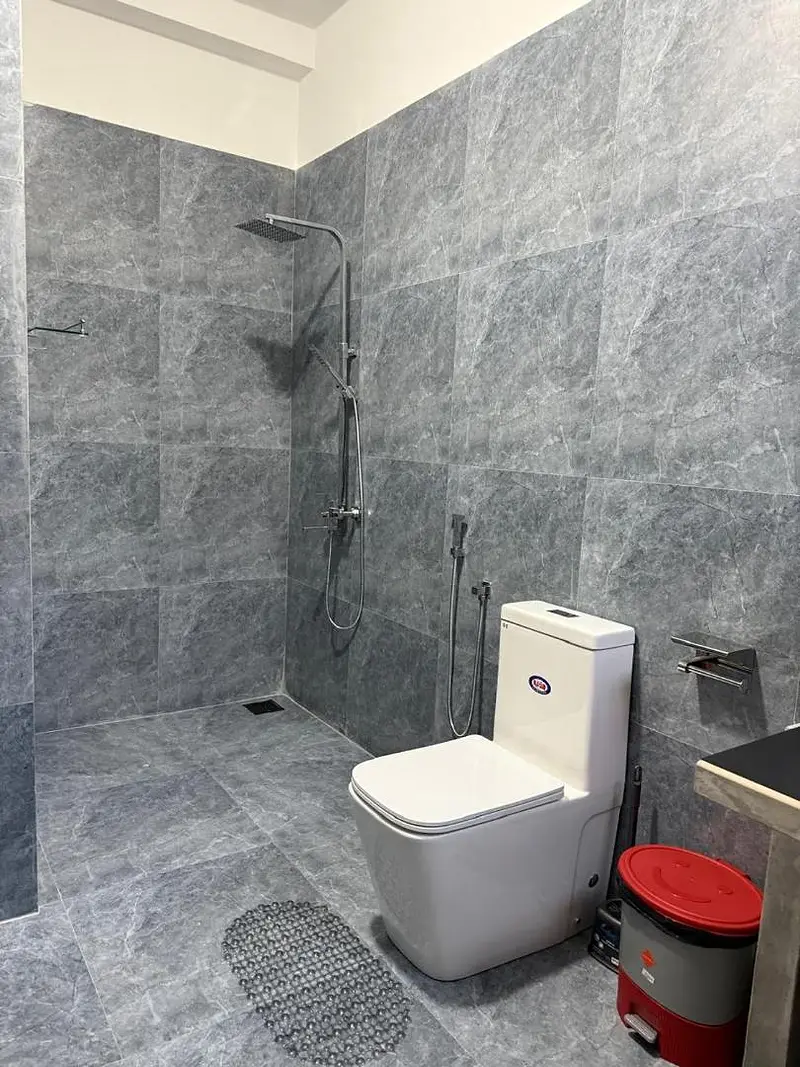 En suite bathroom with grey stone tiles and a rain shower
