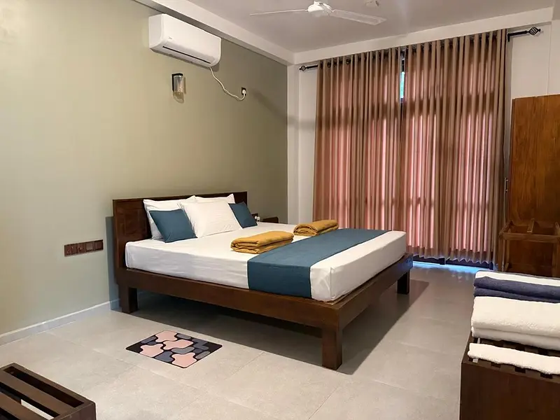 Air-conditioned bedroom with a large timber bed, teal runner and long curtains