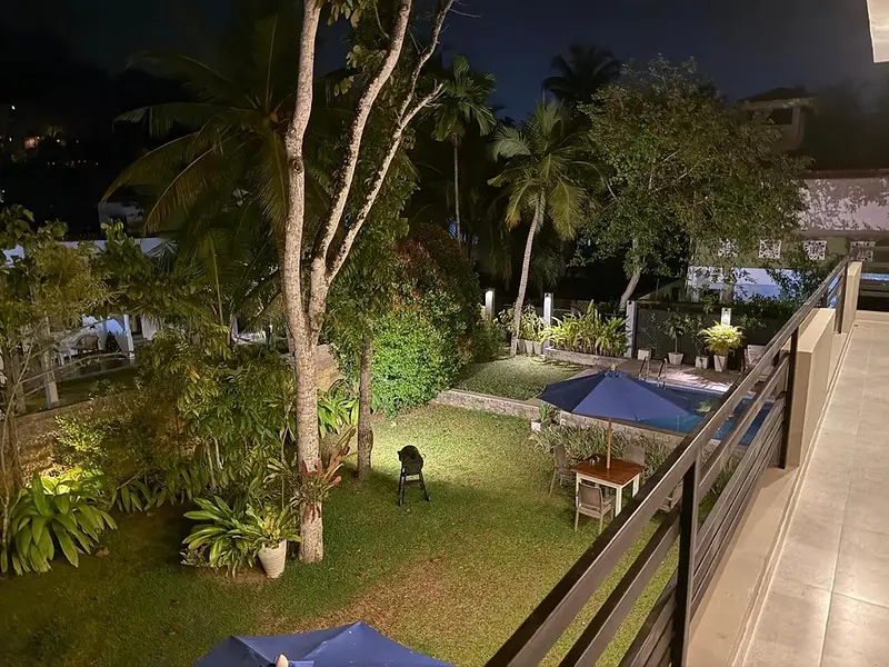 Looking down from the first-floor balcony over the lit garden at night