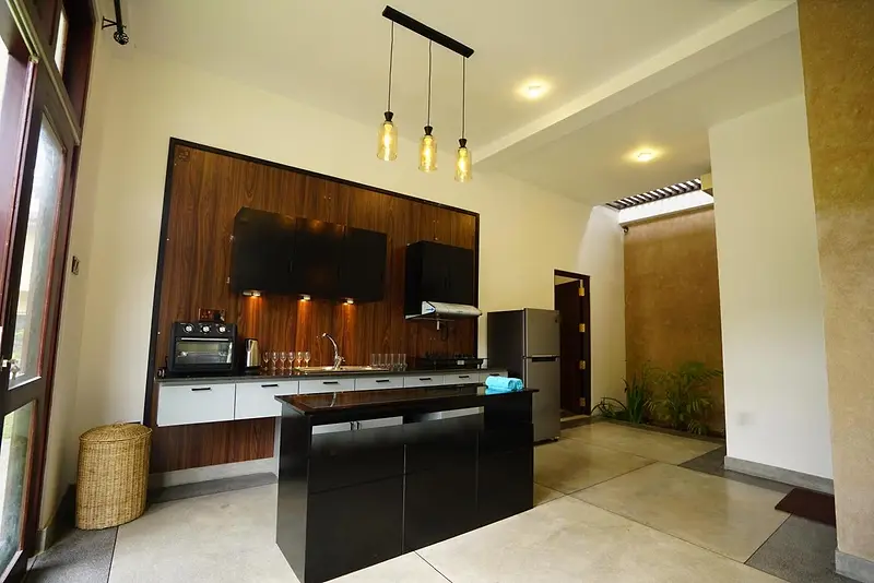 Kitchen with a black island, pendant lights and timber feature wall