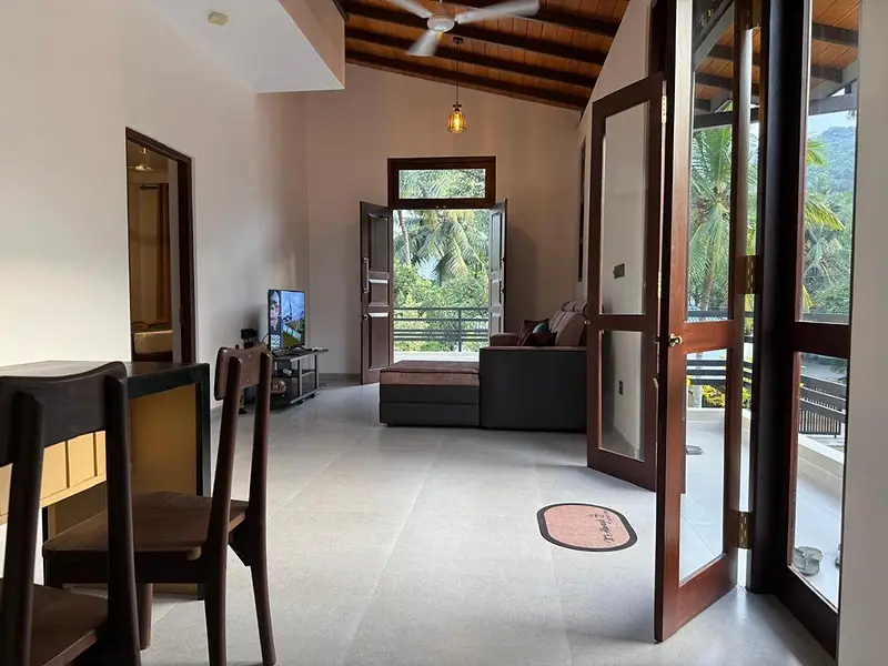 Open-plan living and dining room with a timber ceiling and doors open to the trees