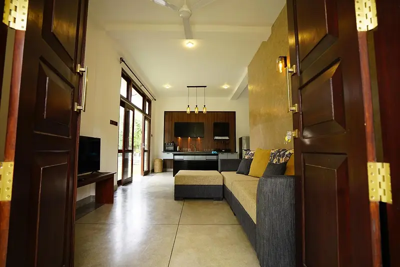 Lounge with sofa leading through to the kitchen, seen through timber double doors