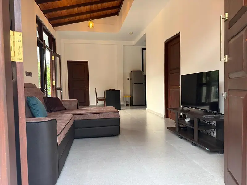 Lounge with a large L-shaped sofa, television and tall windows