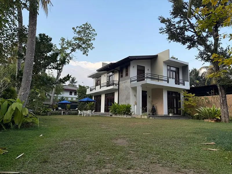 Wide view of the villa and its large garden framed by tall trees