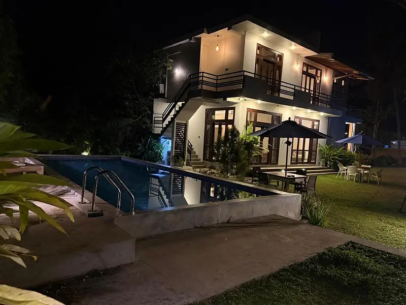 Yehen's Villa at night: the two-storey white house lit up behind its glowing private pool